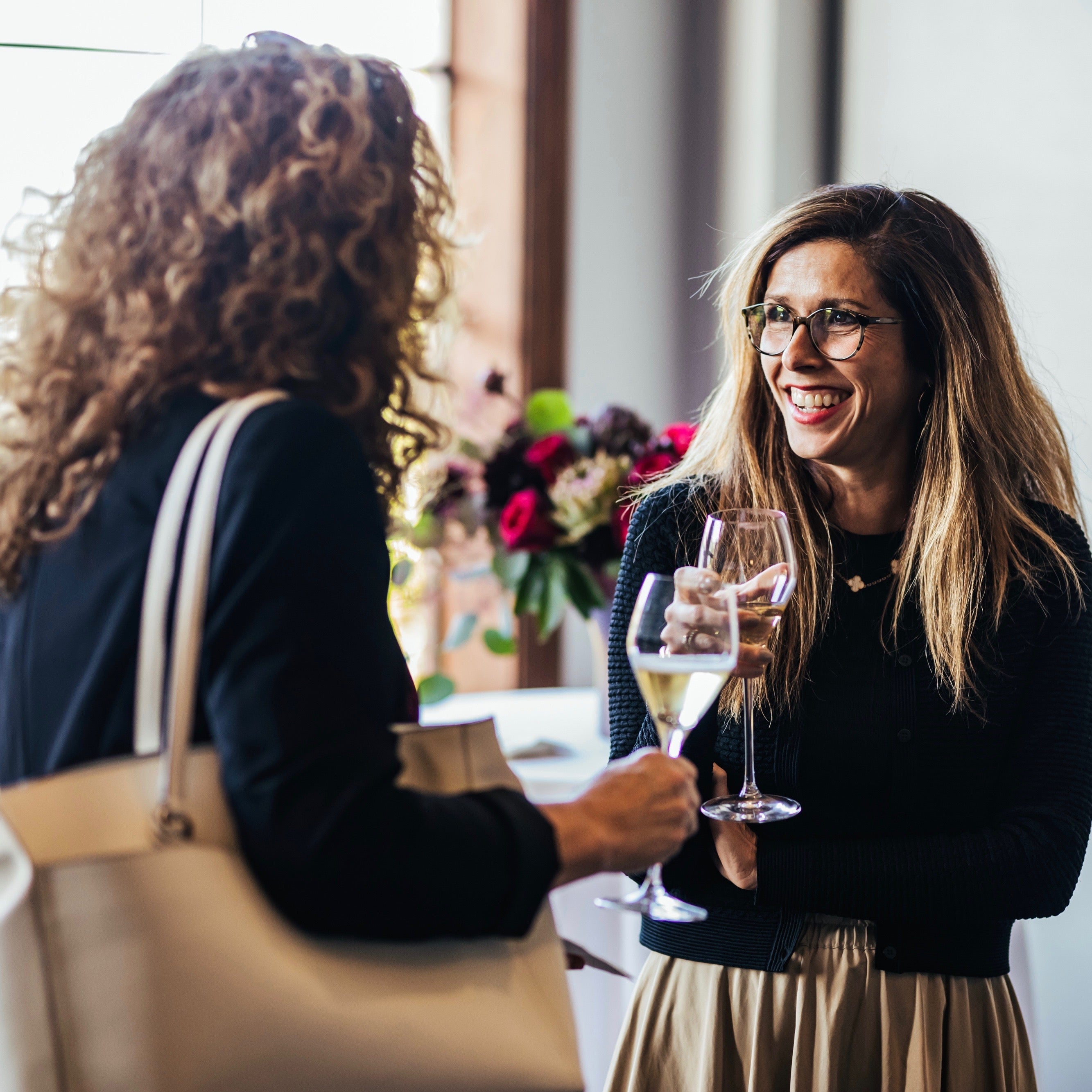 Two Women Holding Champagne Glasses in a brightly lit room at San Francisco Wine School