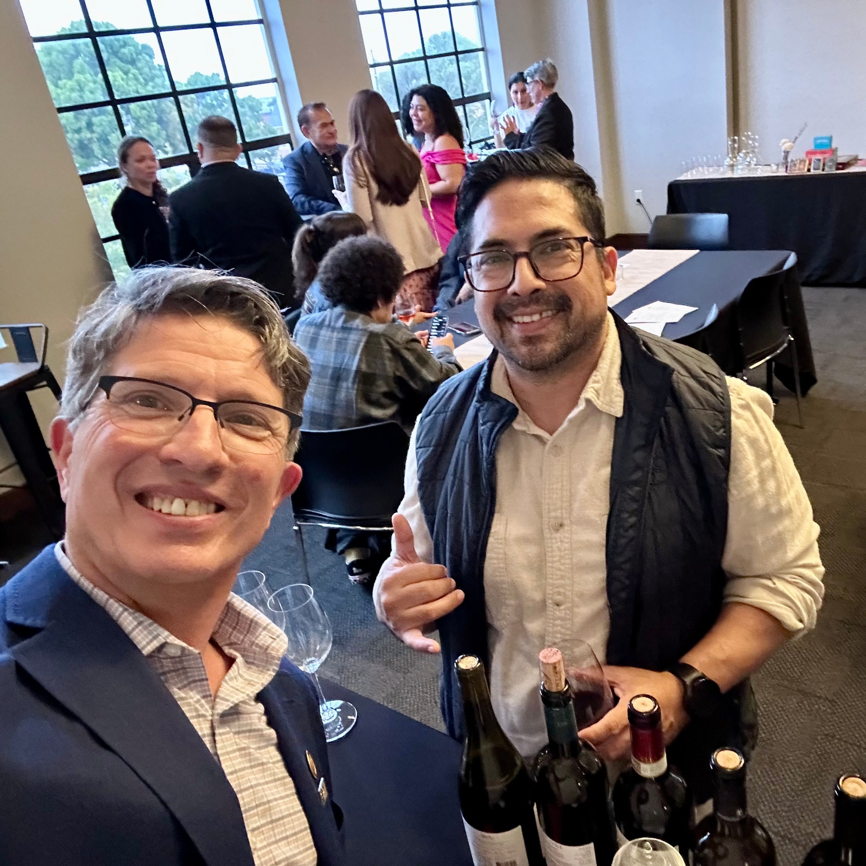 Two men standing together with bottles of wine in a social setting in the Secret Wine Bar at San Francisco Wine School