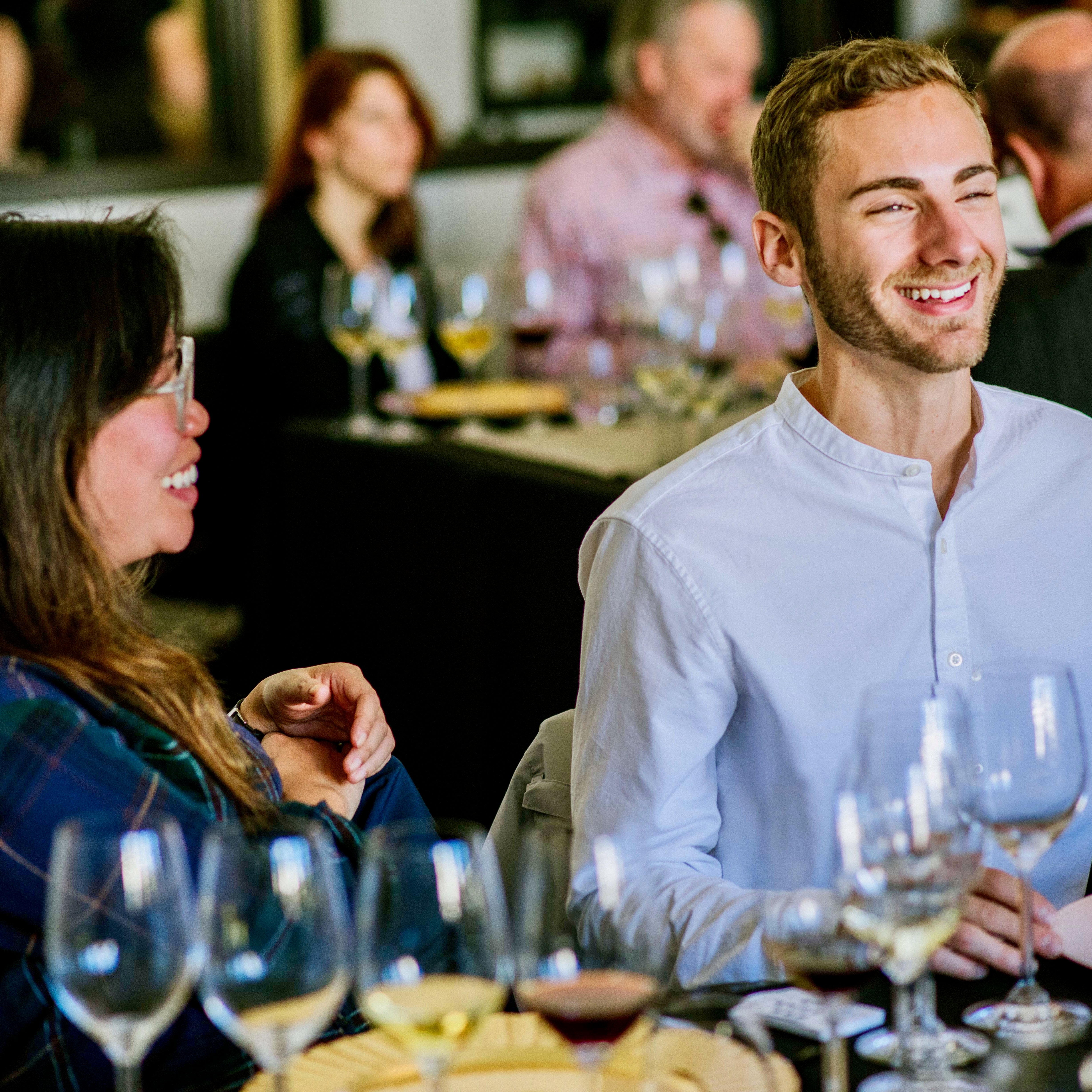 Two people sitting at a table with wine glasses at San Francisco Wine School learning about wine tasting.