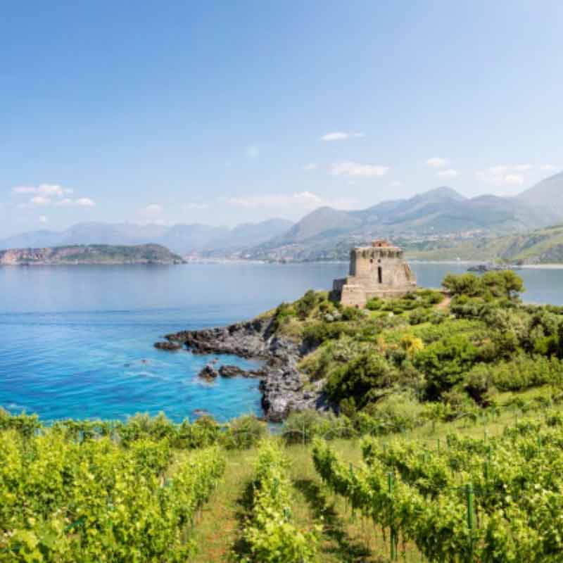 A fortress on a bay with mountains and islands in the distance in Calabria, Italy
