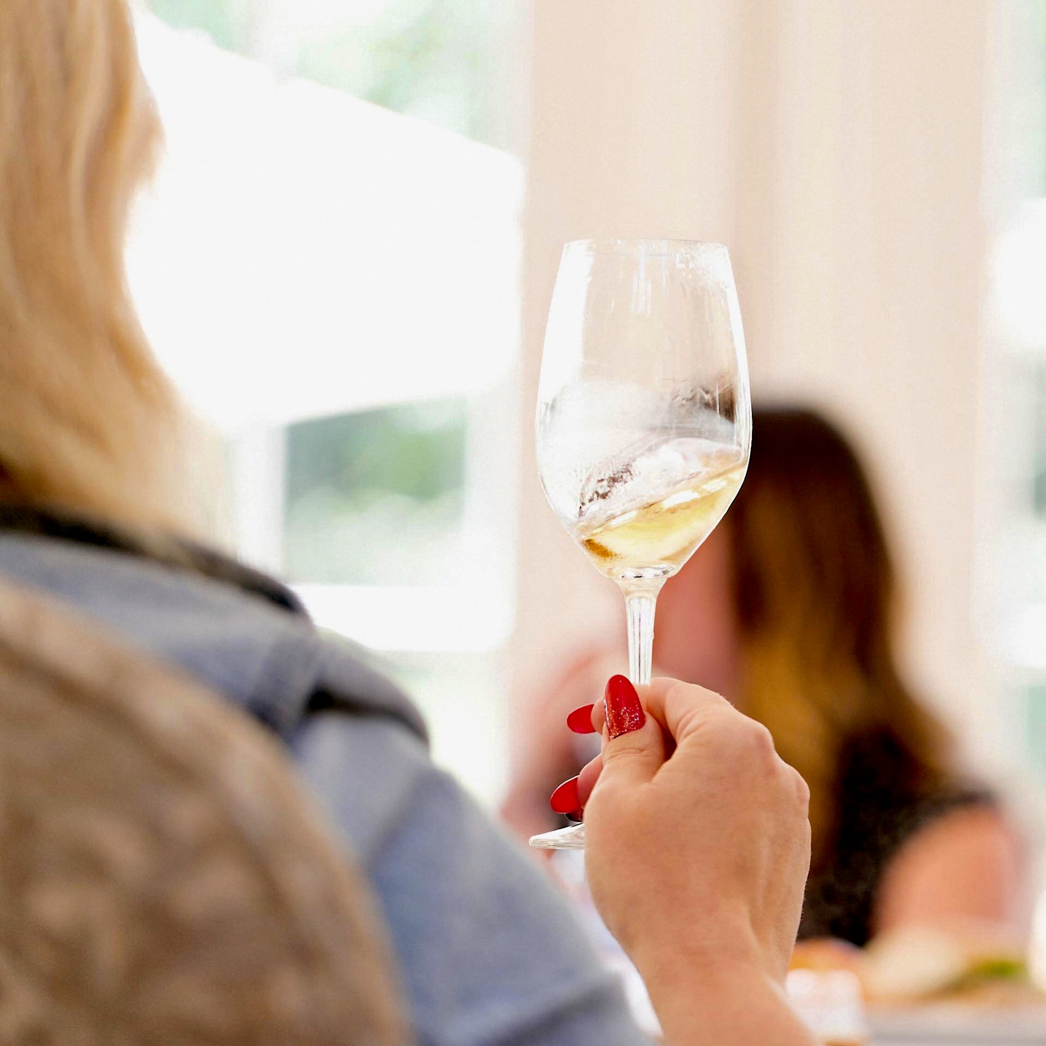 Person holding a glass of white wine learning about tasting, drinking and ordering wine with education from San Francisco Wine School.